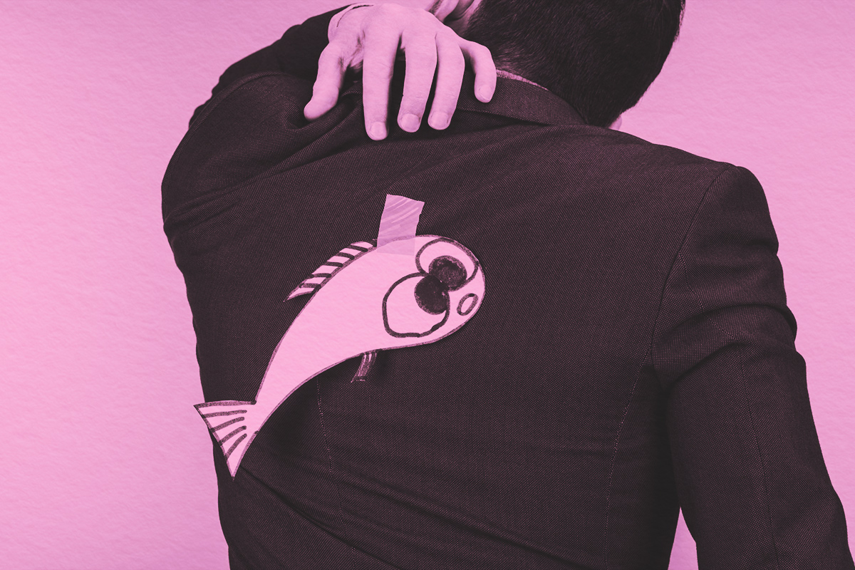 back view of businessman in suit with paper made fish on back, april fools day concept