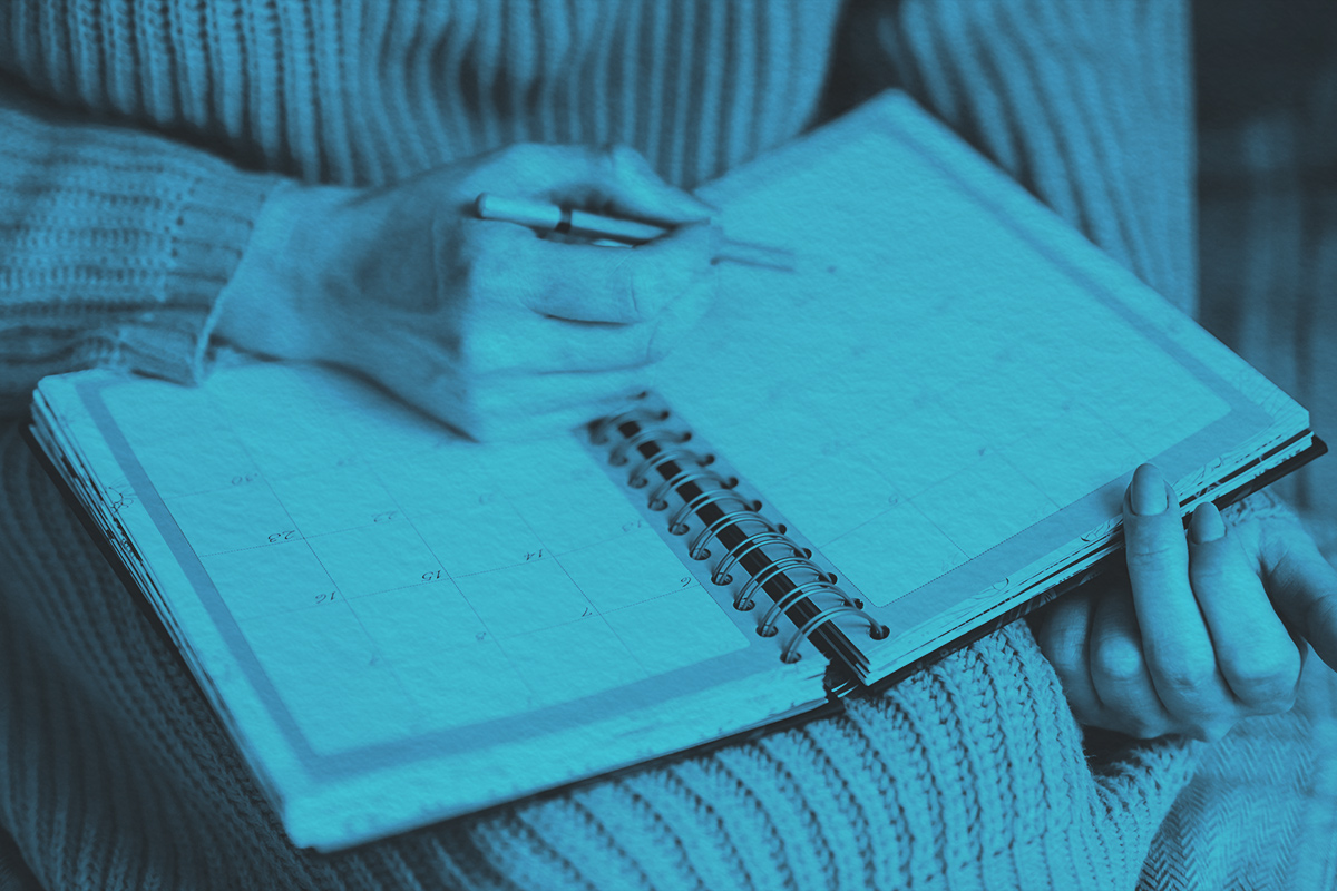 Woman writing in monthly planner