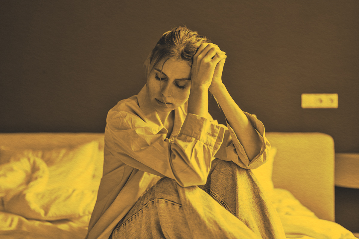 unhappy woman sitting on bed at home