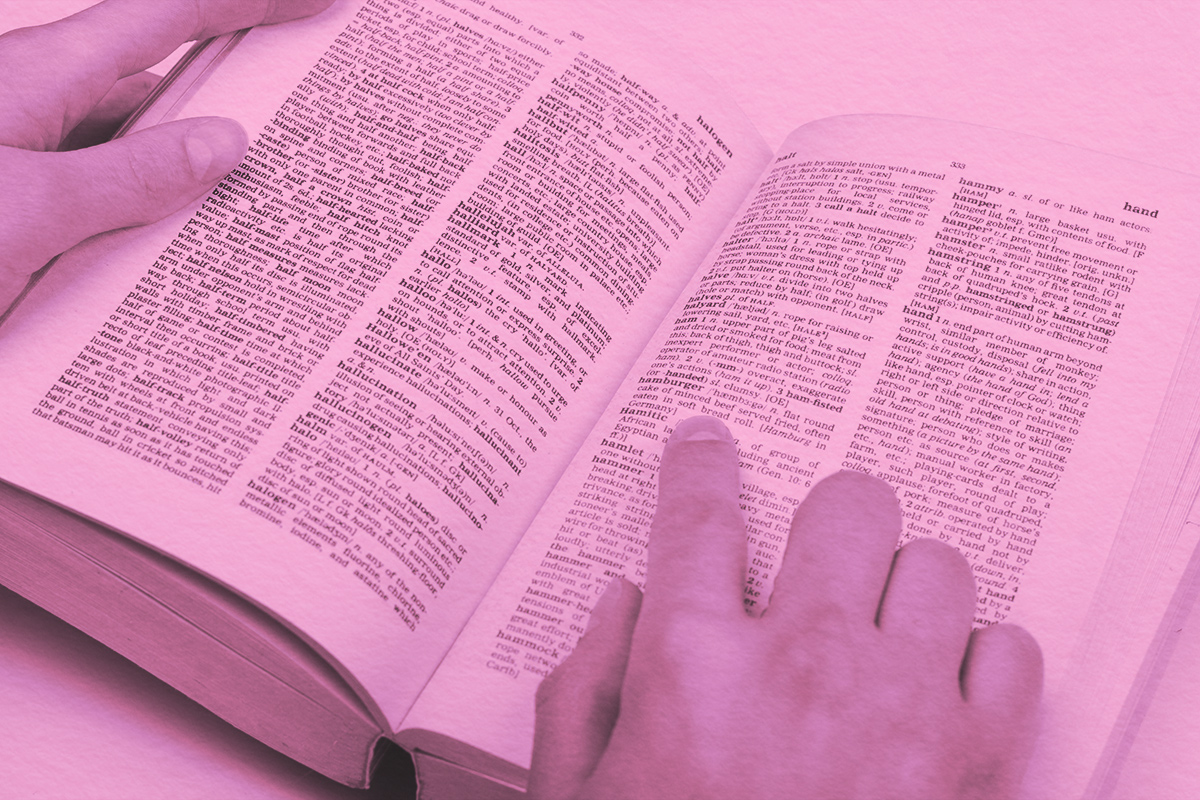 Close-up of a student's hand pointing at a word in a dictionary