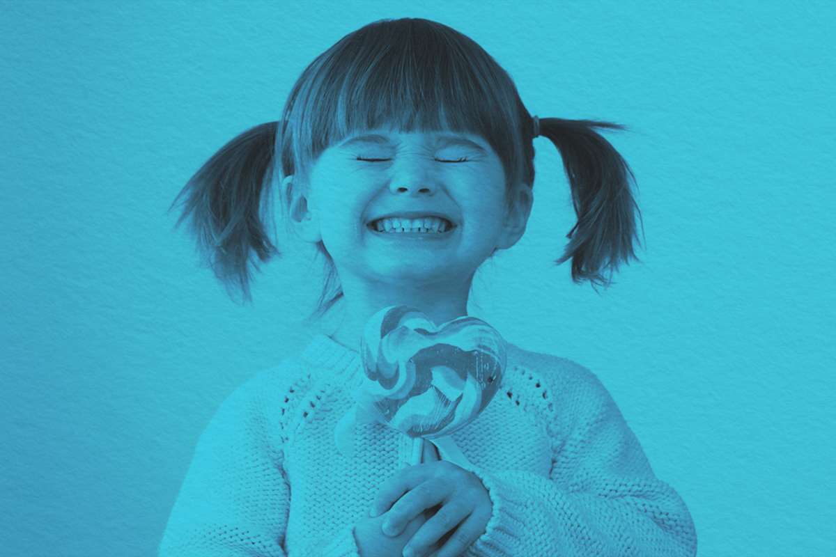 Giddy young girl with a heart-shaped lollipop