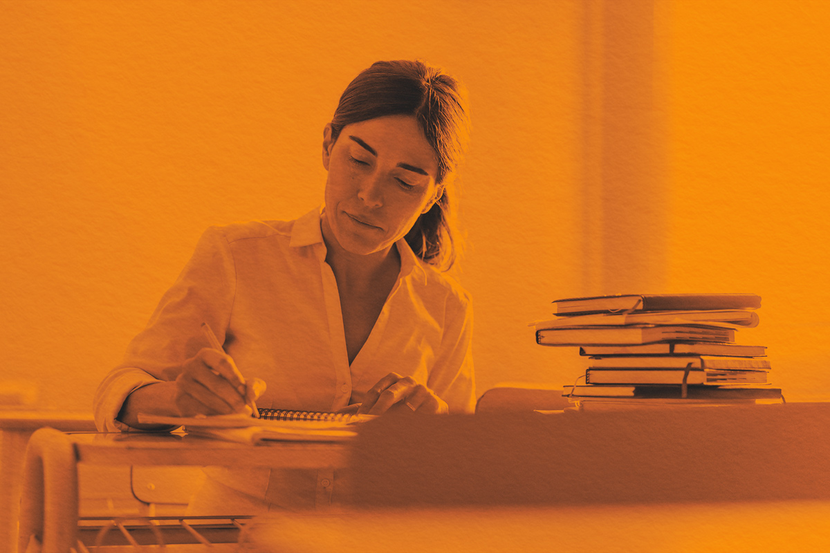 Woman writing in notebook while sitting in a classroom