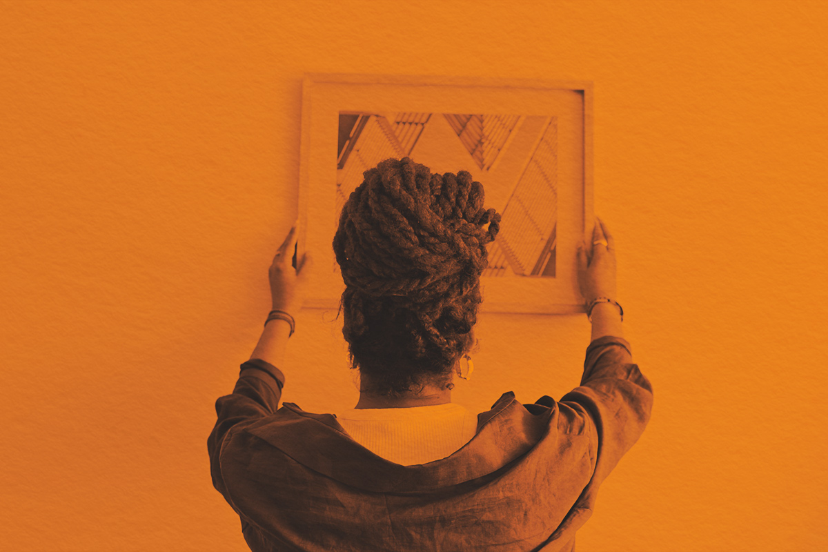 Woman hanging a painting at home