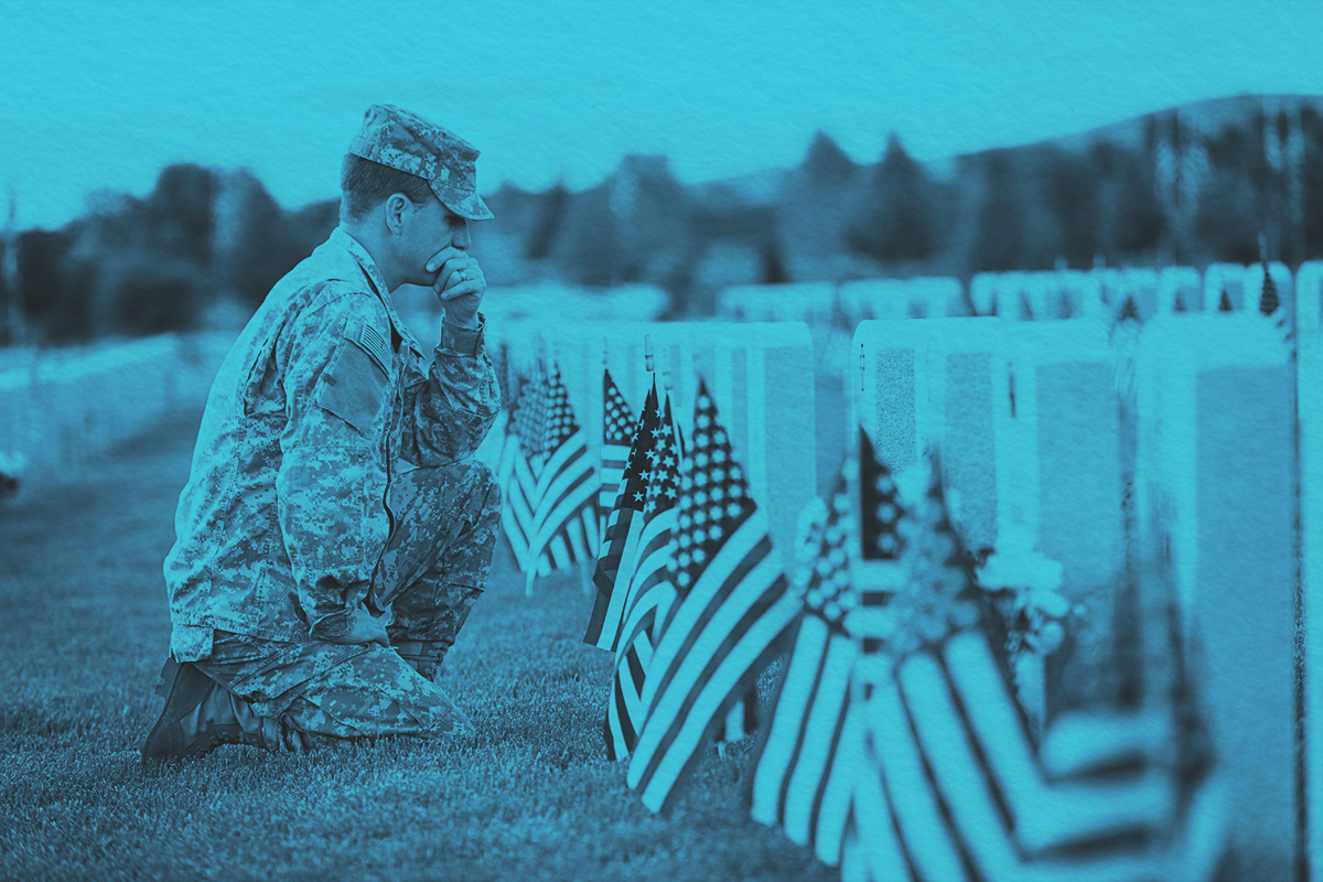 American soldier in uniform on memorial day, kneeling at tombstone