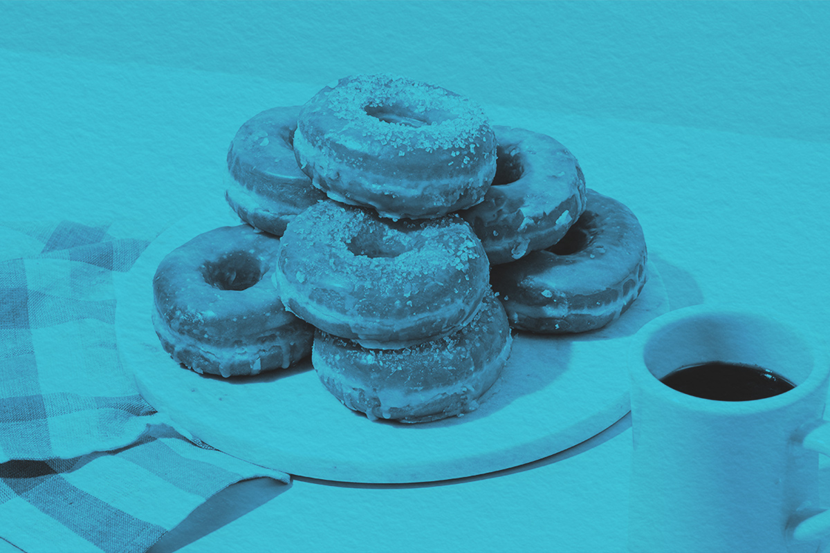Stack of donuts on a table next to a cup of coffee