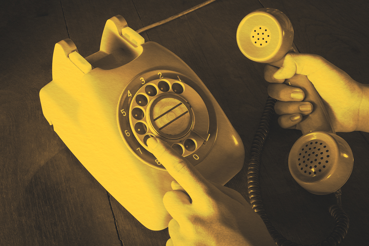 Close up of a hand holding a rotary telephone and dialing a number