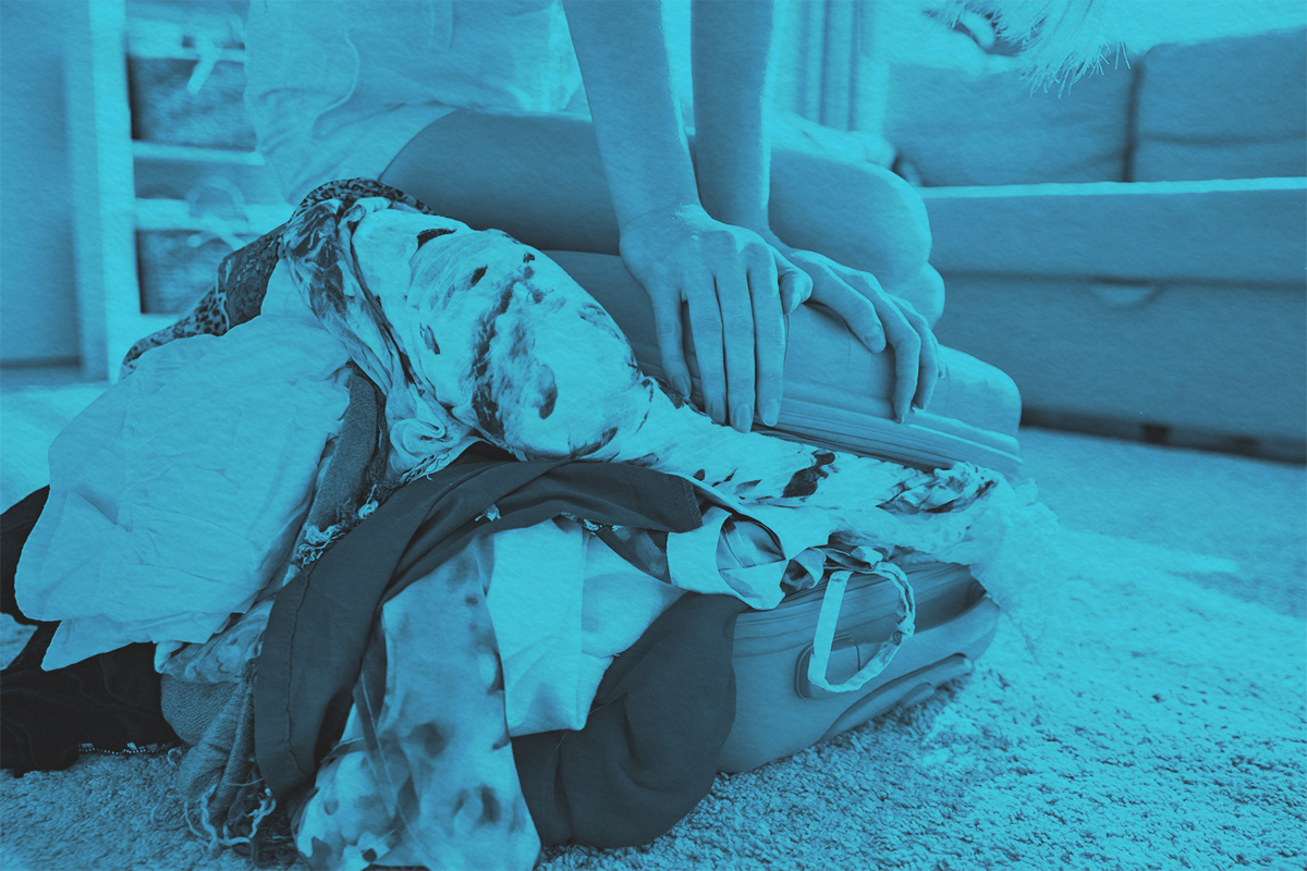 Girl packing overflowing suitcase for travel