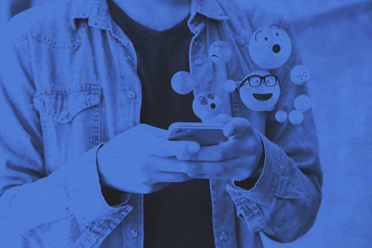 Close-up of a man using a smartphone to send emojis