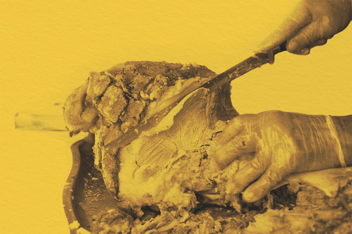 Man with knife cutting slices of the roasted pork