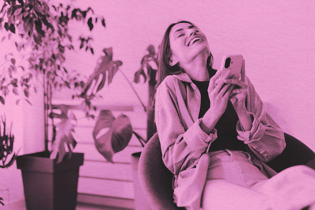 Woman laughing while looking at her phone