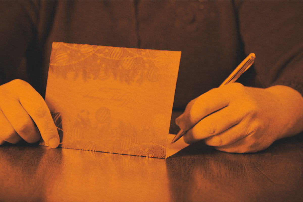 Woman Writing Holiday Cards On Table