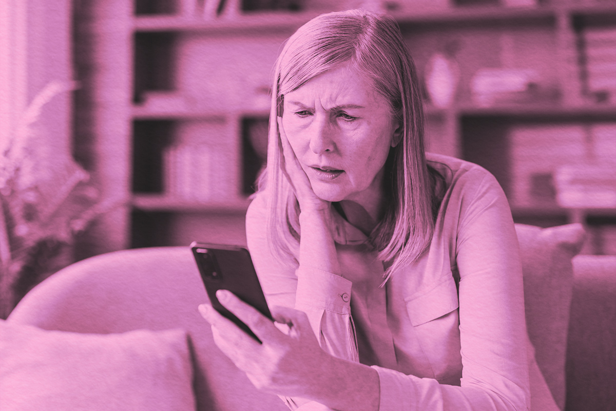 woman on sofa while looking at smartphone