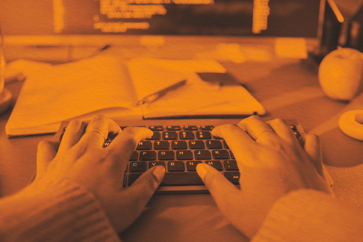 Woman Typing on Wireless Keyboard While Working at Desk