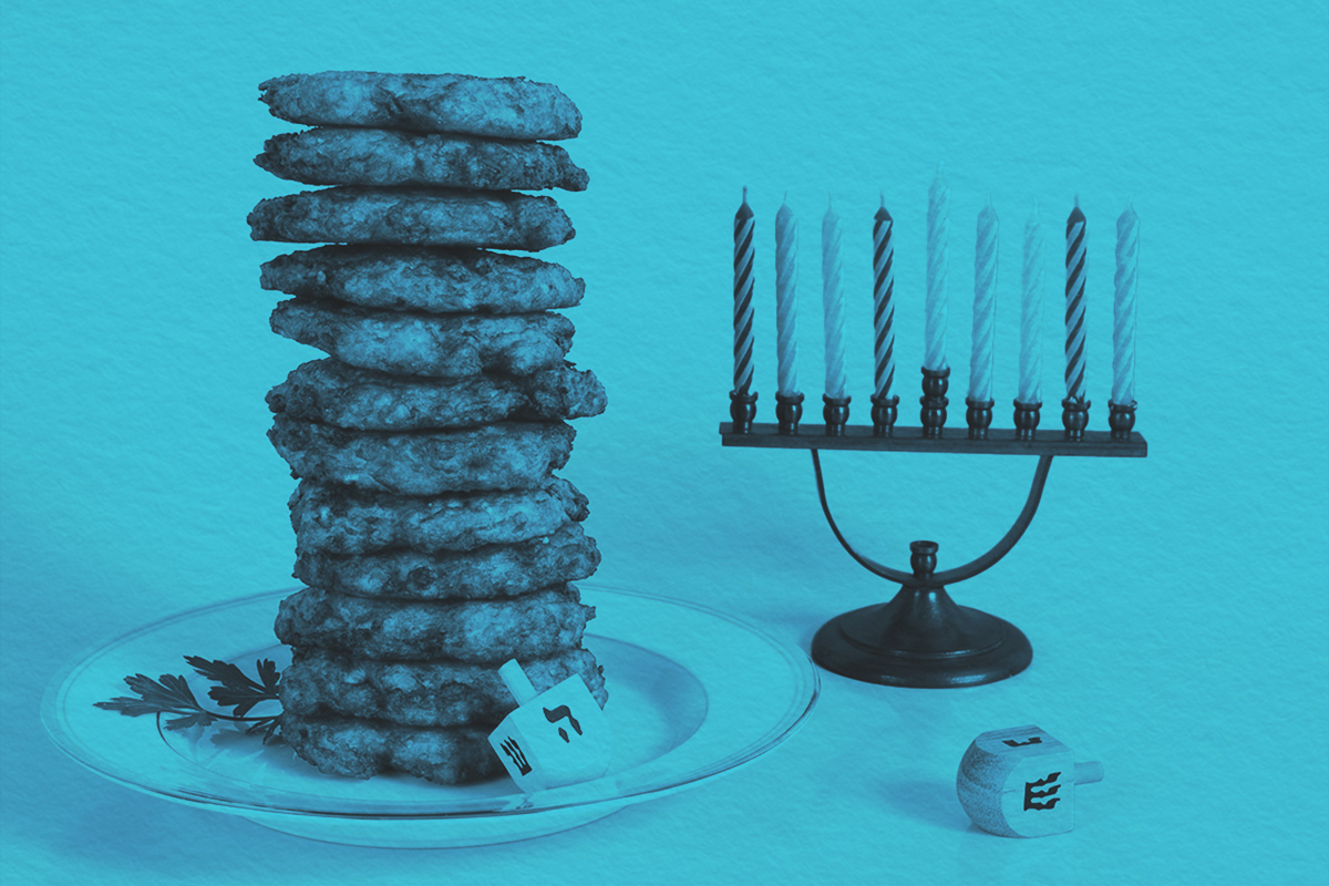 A dozen crispy fried potato latkes for Hanukkah ,next to a dreidel and a menorah
