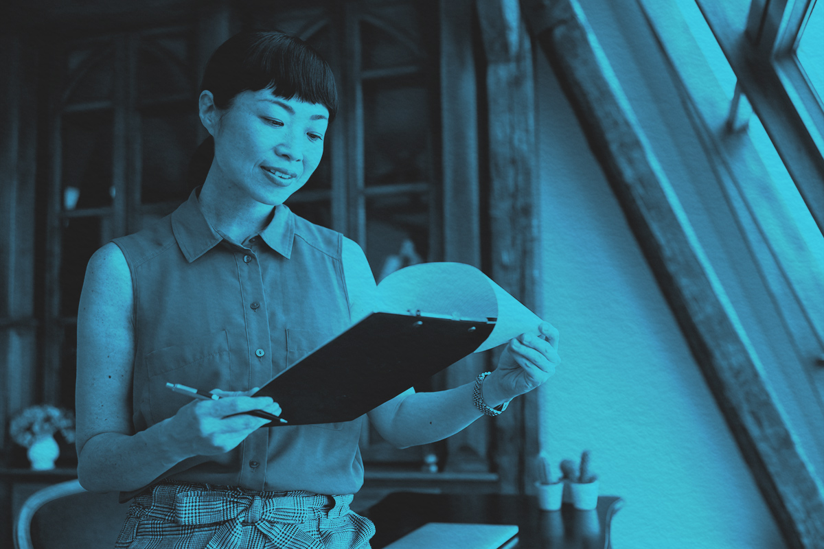 A woman reviewing and signing contracts and documentation