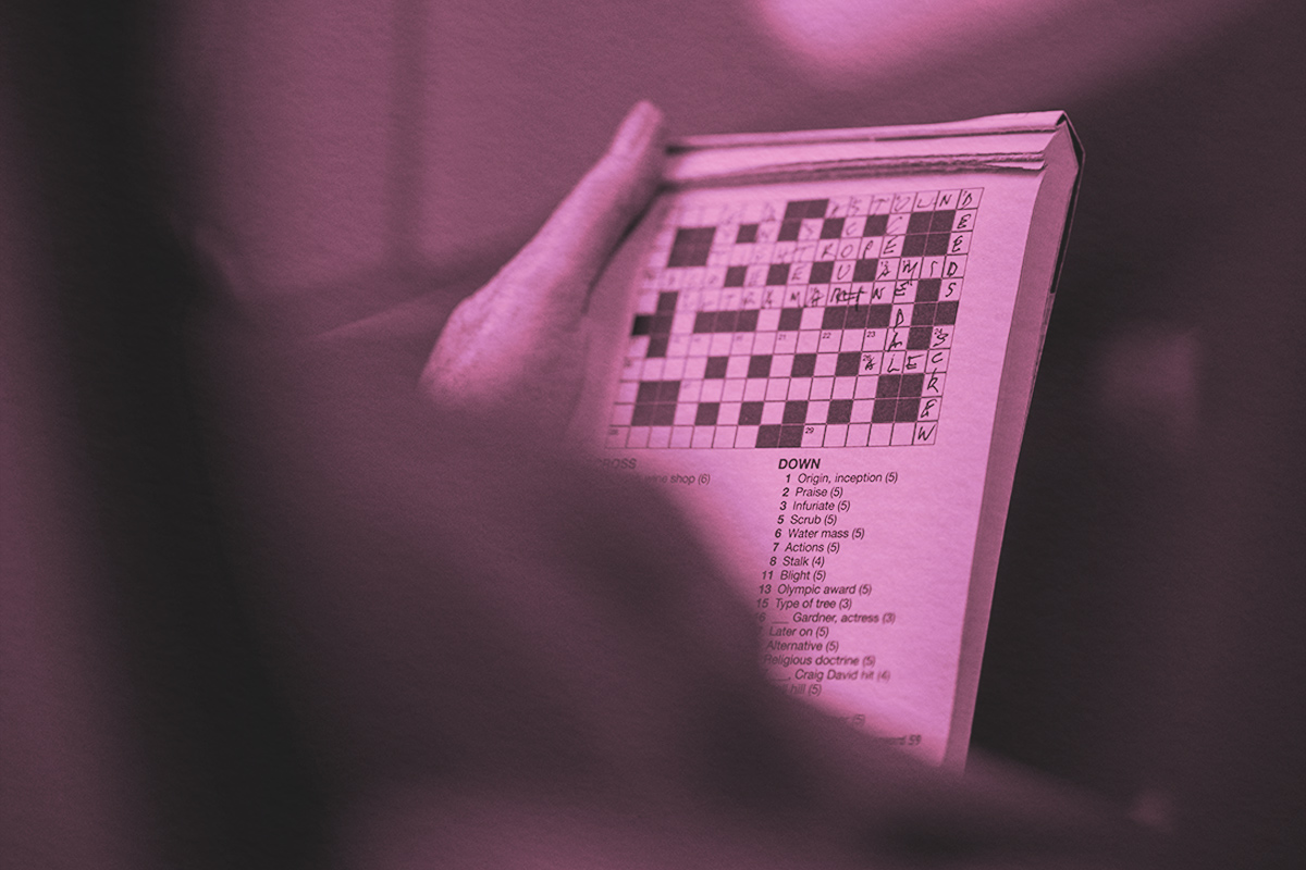 Person holding and working on a crossword puzzle