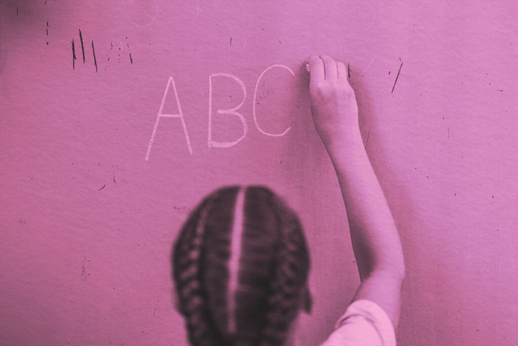 Student writes alphabet letters on school board