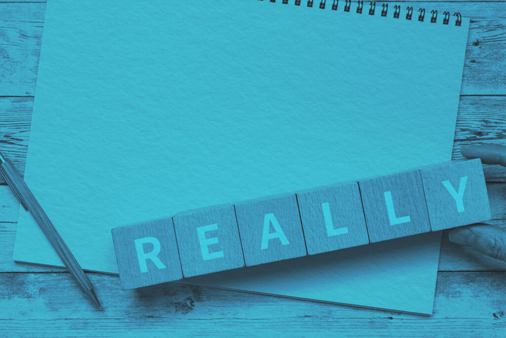Wooden blocks with "REALLY" text next to a pen and notebook paper