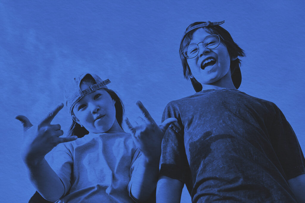 A boy and a girl make faces at the camera against the background of the sky